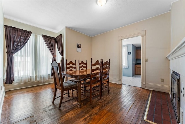 dining area with dark wood-style floors, a fireplace, and baseboards