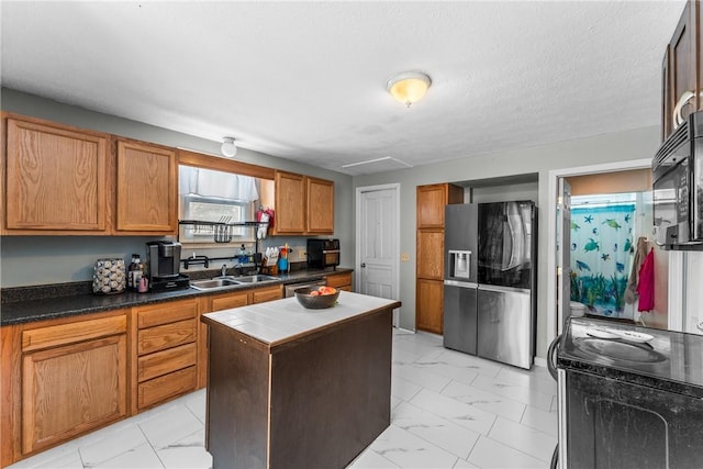 kitchen with marble finish floor, stainless steel appliances, a sink, and a center island