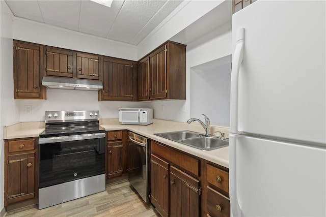 kitchen featuring light countertops, appliances with stainless steel finishes, a sink, dark brown cabinets, and under cabinet range hood