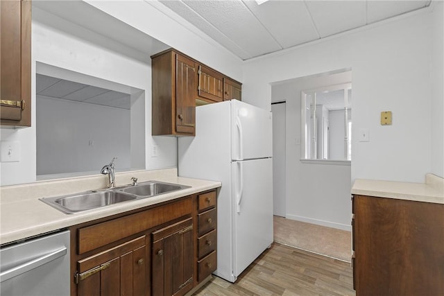 kitchen featuring freestanding refrigerator, light countertops, a sink, and stainless steel dishwasher