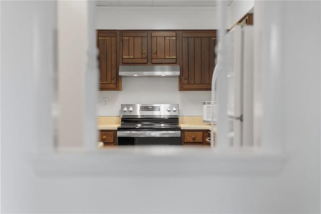 kitchen with stainless steel electric range oven, light countertops, freestanding refrigerator, and under cabinet range hood