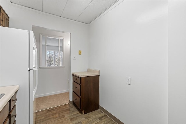 kitchen with light countertops, wood finished floors, freestanding refrigerator, and baseboards