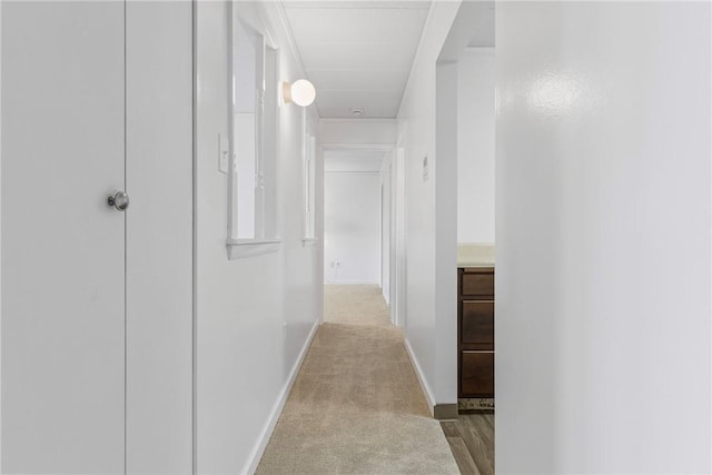 corridor featuring baseboards and light colored carpet