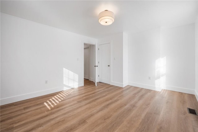 spare room featuring visible vents, light wood-style flooring, and baseboards