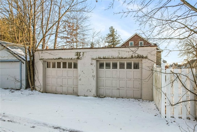 snow covered garage with a detached garage