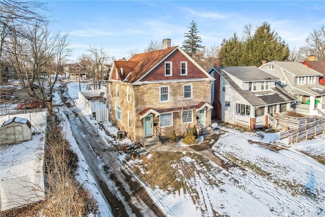 exterior space with a residential view, stone siding, cooling unit, and a chimney