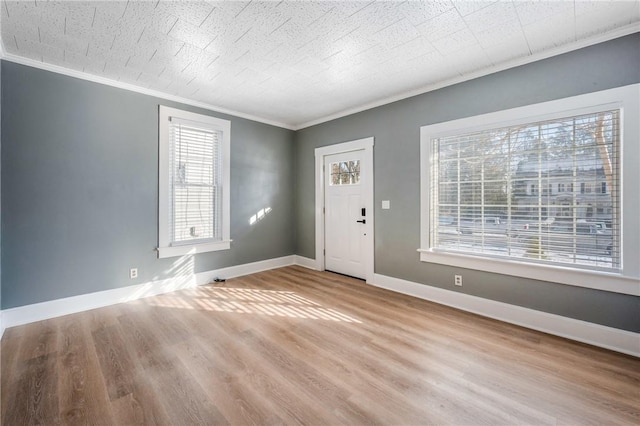 foyer entrance featuring crown molding, light wood finished floors, and baseboards