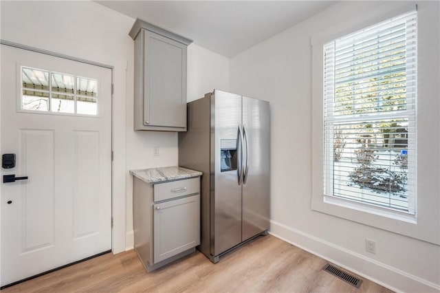 kitchen with stainless steel fridge, visible vents, light wood-style flooring, and gray cabinetry