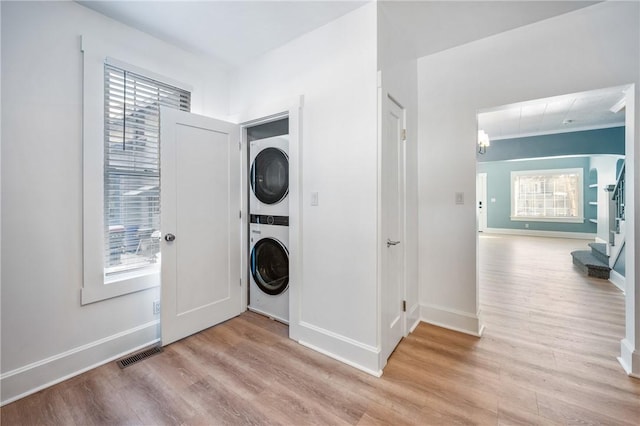 washroom with plenty of natural light, stacked washing maching and dryer, visible vents, and laundry area