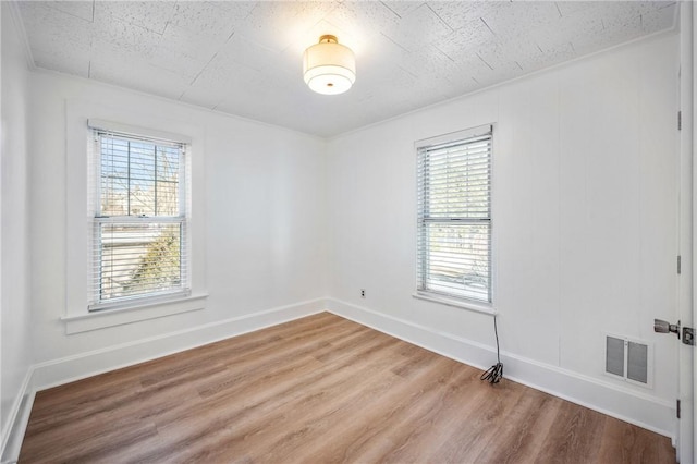 empty room with baseboards, visible vents, and wood finished floors