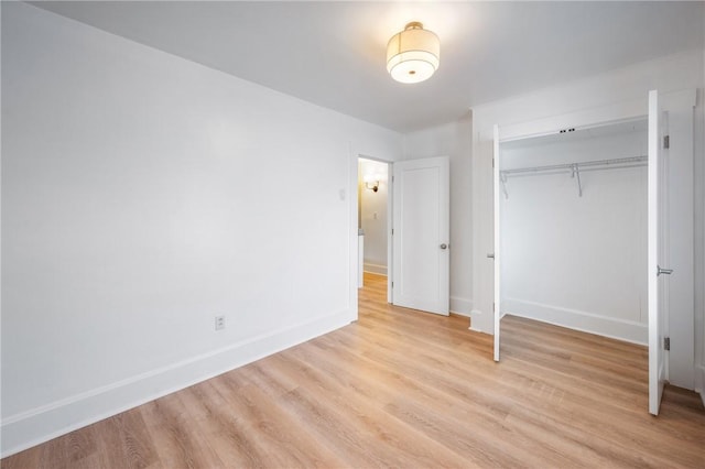 unfurnished bedroom with light wood-type flooring, baseboards, and a closet