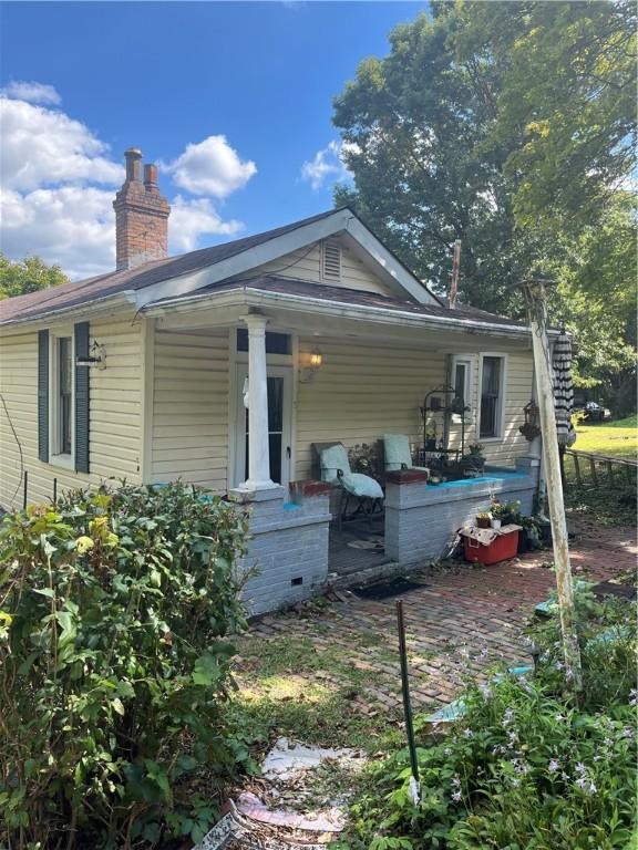 back of house with crawl space and a chimney