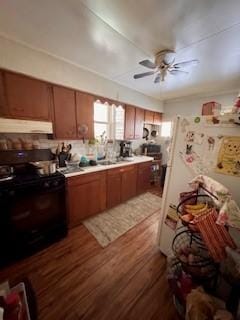 kitchen with dark wood-style flooring, freestanding refrigerator, light countertops, black range, and under cabinet range hood