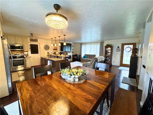 dining space with a notable chandelier, a textured ceiling, baseboards, and dark wood-style flooring