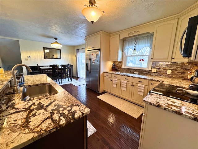 kitchen with plenty of natural light, dark wood finished floors, a sink, and stainless steel fridge with ice dispenser