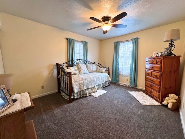 bedroom with multiple windows, dark colored carpet, and a textured ceiling