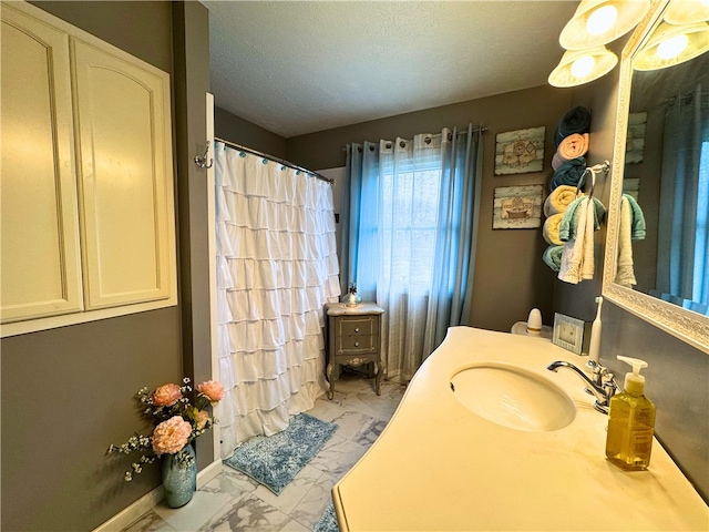 full bathroom with a textured ceiling, vanity, baseboards, marble finish floor, and a shower with curtain