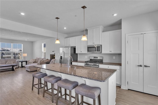 kitchen featuring appliances with stainless steel finishes, open floor plan, a kitchen island with sink, and a sink