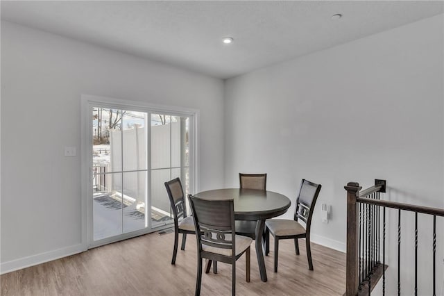 dining space with light wood-type flooring and baseboards