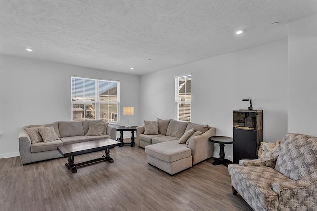 living area with recessed lighting, a textured ceiling, baseboards, and wood finished floors