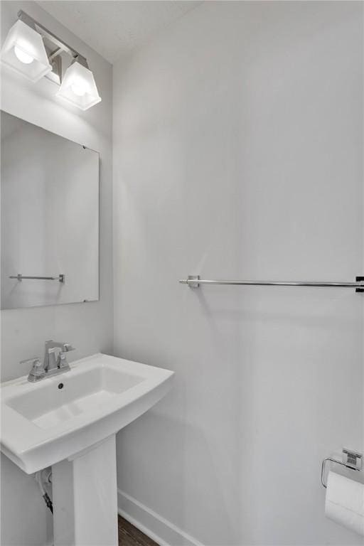 bathroom with a sink, baseboards, and wood finished floors