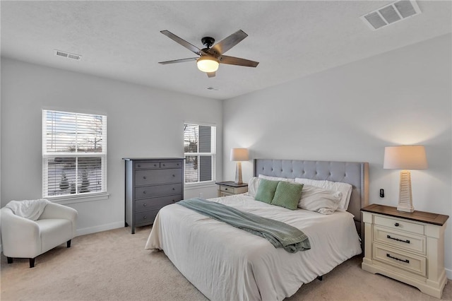 bedroom with light carpet, ceiling fan, visible vents, and baseboards