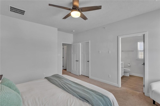 bedroom featuring light carpet, baseboards, visible vents, connected bathroom, and ceiling fan