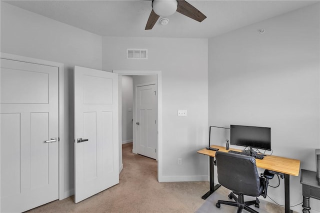 home office featuring baseboards, visible vents, ceiling fan, and light colored carpet