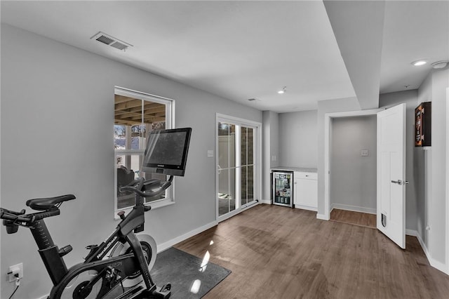 workout area featuring a dry bar, visible vents, wood finished floors, beverage cooler, and baseboards