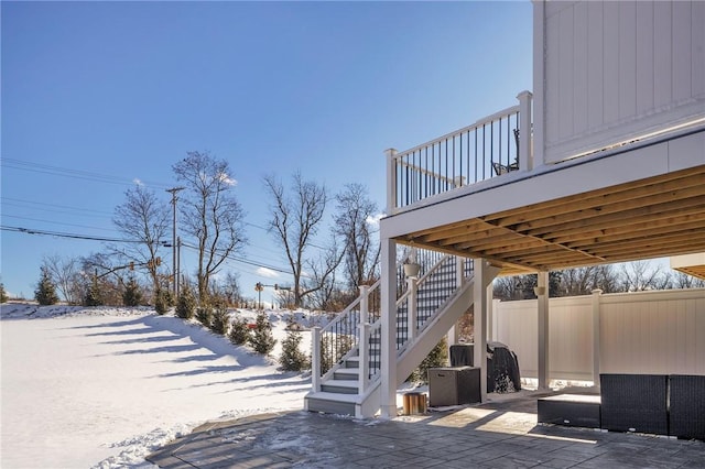 snow covered patio featuring central AC, fence, and stairway