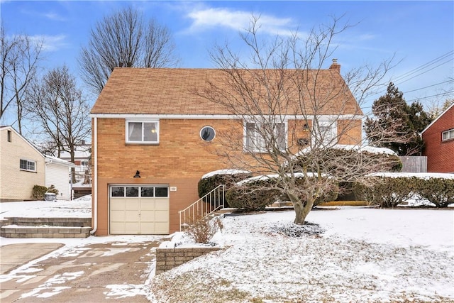 view of front facade featuring brick siding, a chimney, and an attached garage