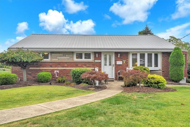 view of front of property featuring metal roof, a front lawn, and brick siding