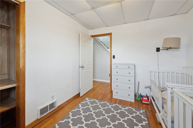 bedroom with visible vents, a drop ceiling, and wood finished floors