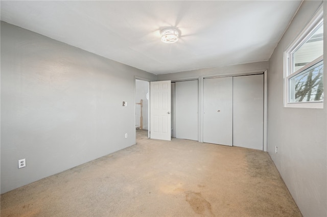 unfurnished bedroom with light carpet and two closets