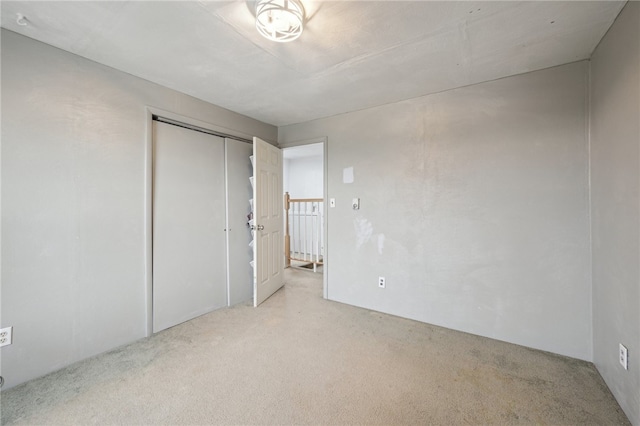 unfurnished bedroom with a closet and light colored carpet