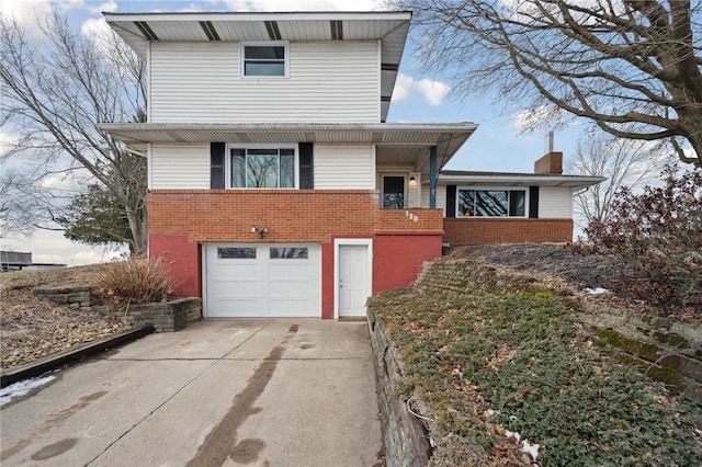 view of front of house with driveway, brick siding, a chimney, and an attached garage