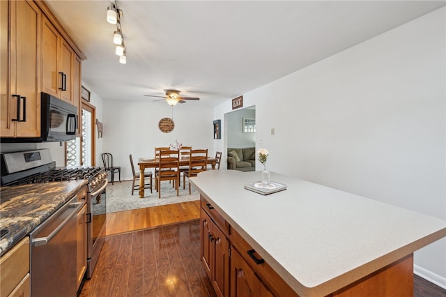 kitchen featuring dark wood-style floors, stainless steel appliances, brown cabinetry, and a center island