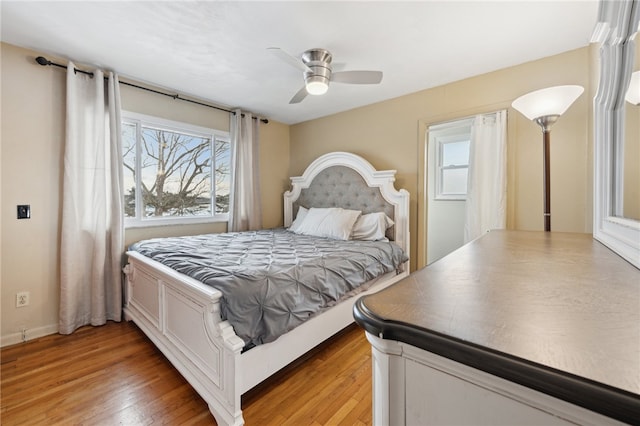 bedroom with multiple windows, a ceiling fan, and wood finished floors