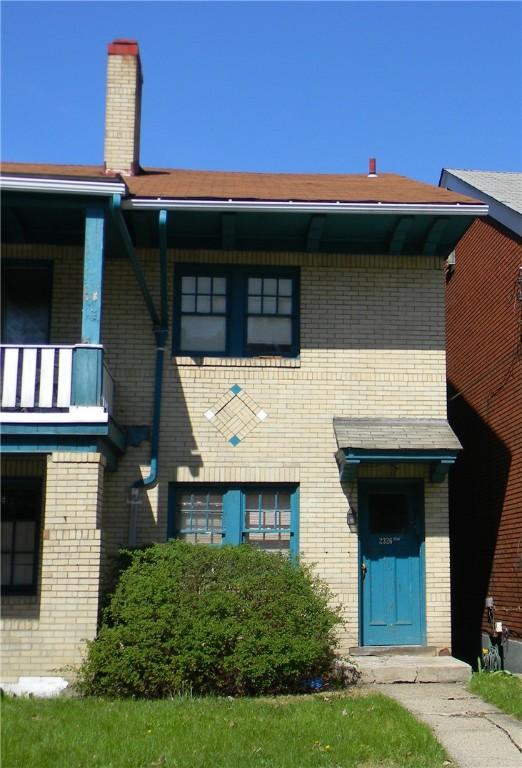 view of front of house featuring brick siding and a balcony