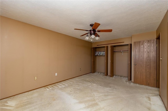 unfurnished bedroom with a textured ceiling, a closet, a ceiling fan, and light colored carpet