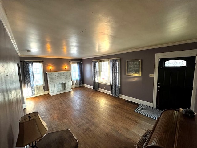 unfurnished living room with dark wood-style floors, ornamental molding, a brick fireplace, and baseboards