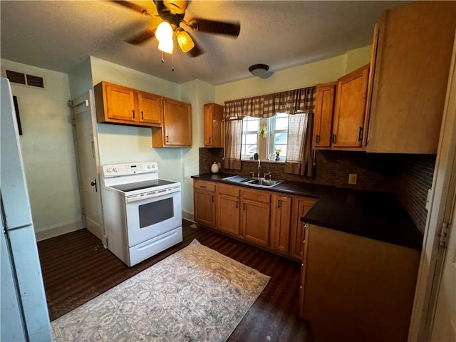 kitchen with white appliances, a sink, visible vents, brown cabinets, and dark countertops