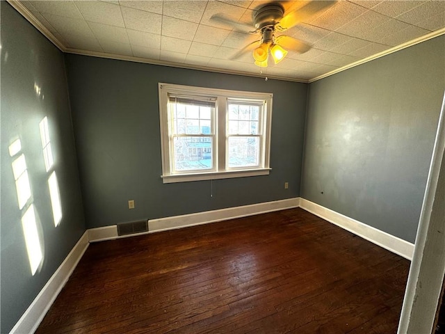 empty room featuring ornamental molding, dark wood-type flooring, visible vents, and baseboards