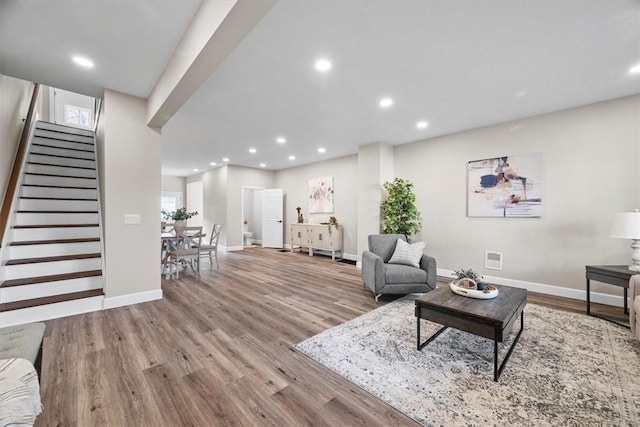 living area featuring stairs, recessed lighting, baseboards, and light wood-style floors