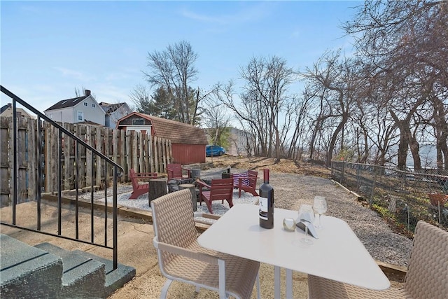 view of patio with outdoor dining space, fence, and a storage unit