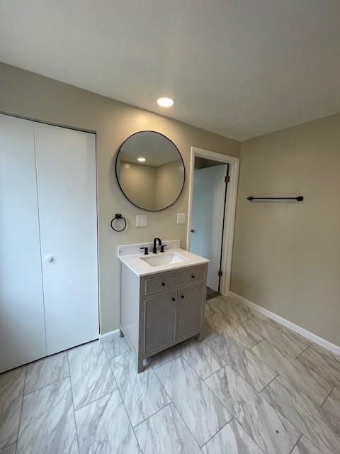 bathroom featuring marble finish floor, vanity, and baseboards