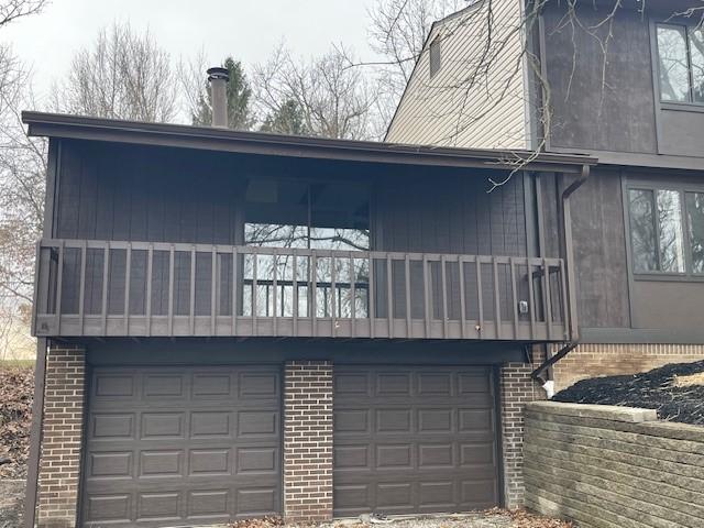 exterior space with brick siding, an attached garage, and a balcony