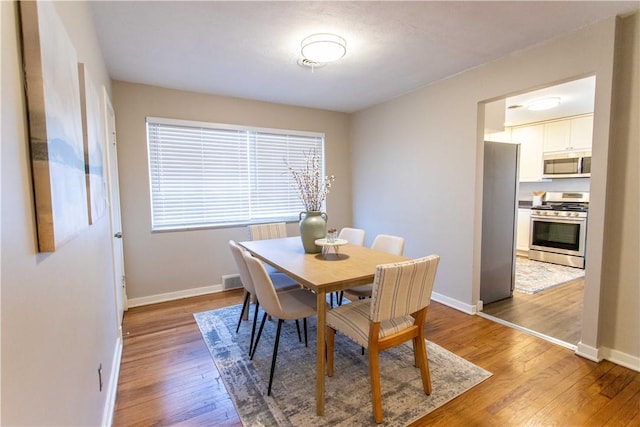 dining space featuring light wood-style floors, visible vents, and baseboards