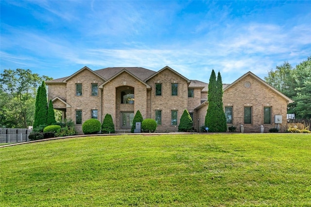 view of front facade with brick siding, fence, and a front yard