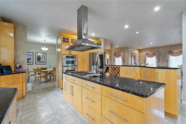 kitchen with island range hood, a spacious island, appliances with stainless steel finishes, dark stone countertops, and glass insert cabinets